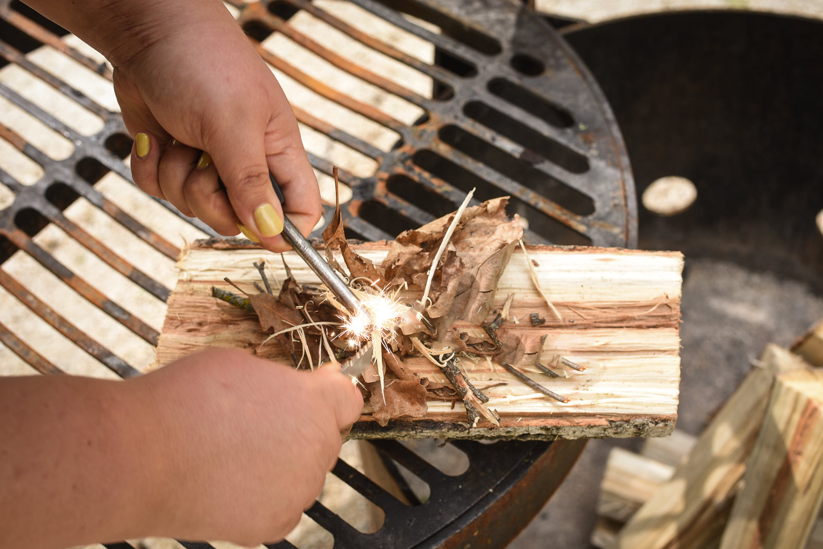 Creating sparks with Coghlan's Flint Striker to ignite wood shavings.